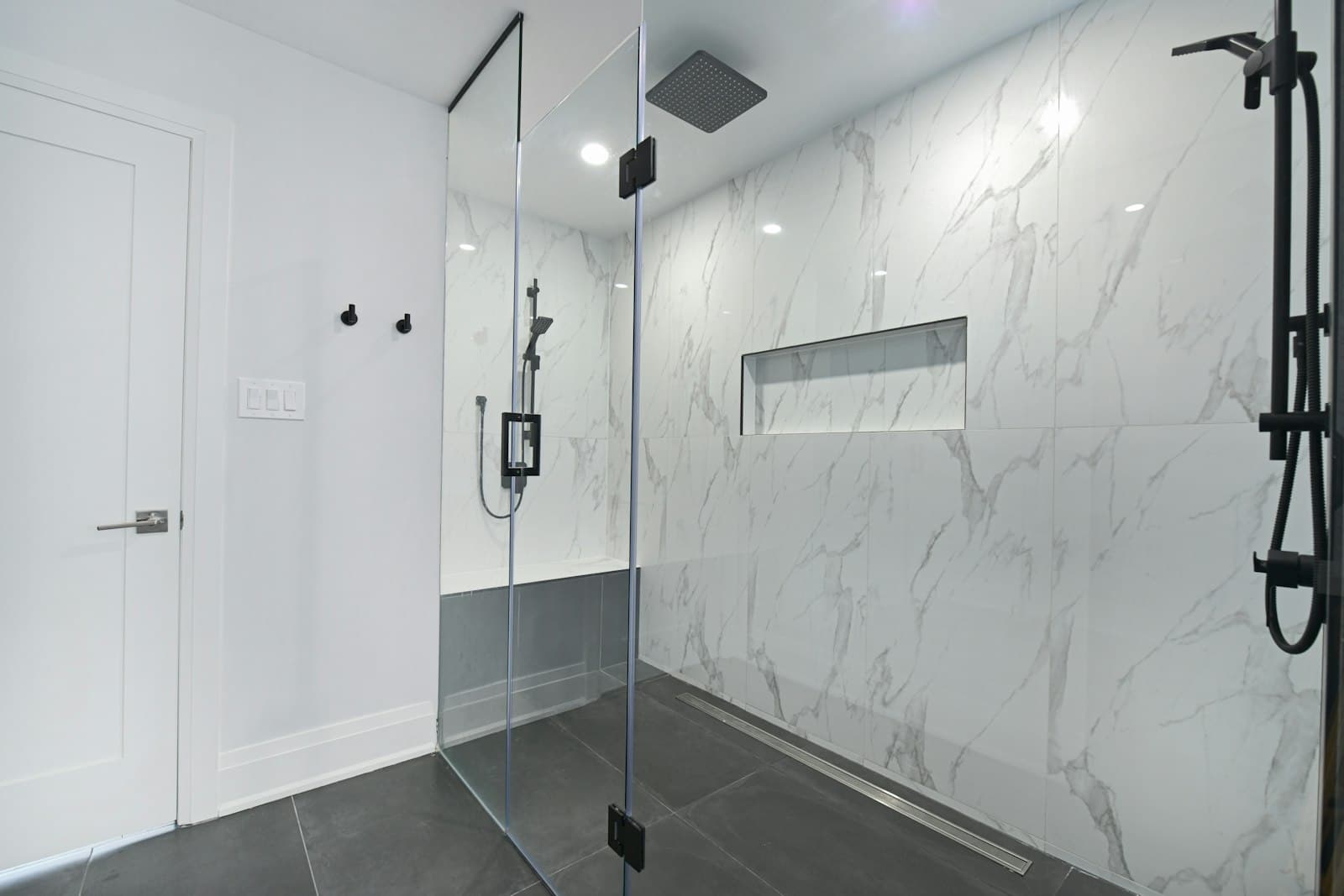 Mermer desenli duvar kaplamaları ve cam duşakabinli modern banyo